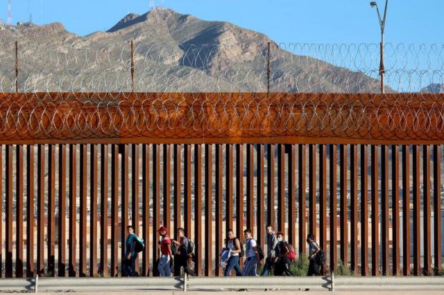 Migrantes venezolanos junto a la valla tras cruzar el río Bravo desde México para entregarse a las autoridades estadounidenses. 22 de septiembre de 2022, El Paso, Texas.