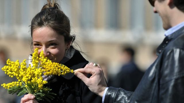 Une femme tient un bouquet de mimosa devant le palais présidentiel italien à l'occasion de la Journée internationale de la femme 2012