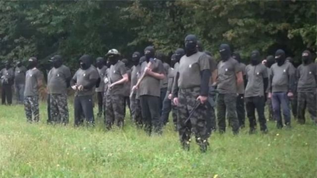 Члени угруповання в масках зі зброєю біля лісу