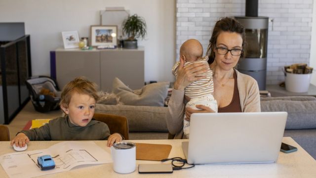 Mujer que trabaja desde casa, con sus dos hijos pequeños