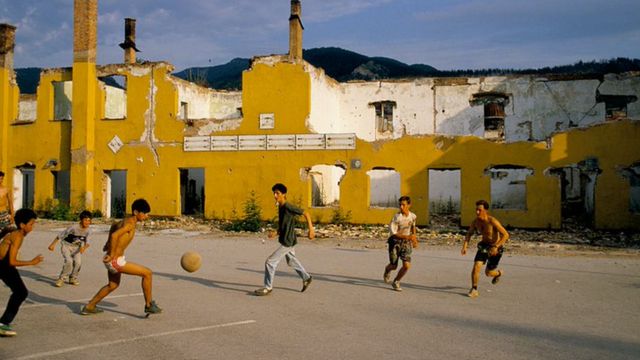 Children play football near the ruins of a bombed building in Sarajevo in 1993
