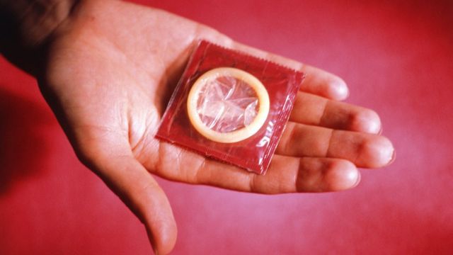 Mano mostrando preservativo.