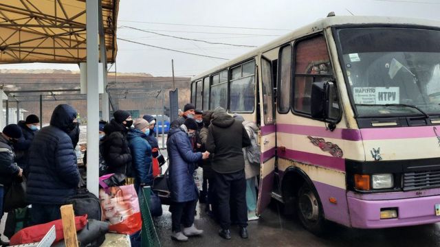أشخاص يتعجلون الصعود إلى الحافلة عند نقطة التفتيش هرباً من البرد