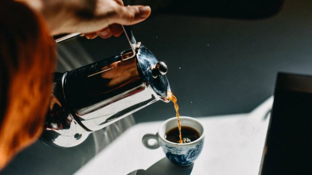 Mulher jovem e bonita com uma xícara de café de plástico na mão