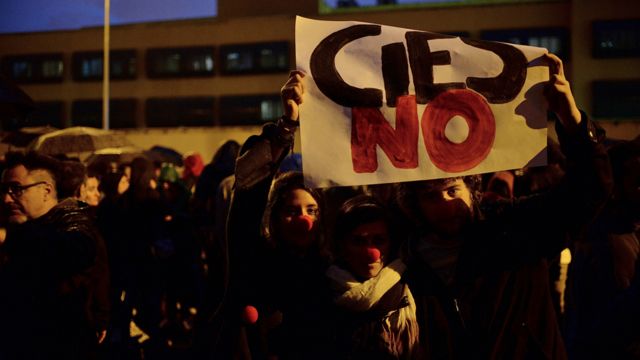 Protestas frente al centro de internamiento de extranjeros en Aluche, Madrid, con un cartel que reza "Cies NO"