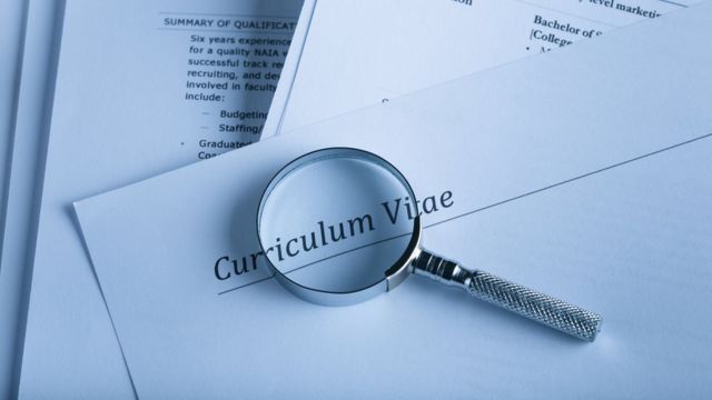 An image showing a magnifying glass over a resume.