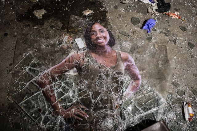 17. An advertisement from a storefront lies on the ground with shattered glass during protests resulting from the killing of an unarmed black man, George Floyd, by police.