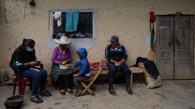 A family in Cajamarca is shelling corn on the outskirts of a rustic house.