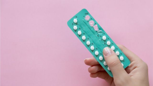 A photo of conceptive pills on a pink background
