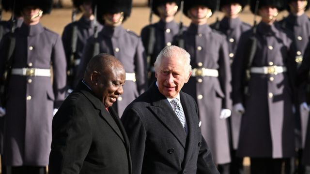 The King and South African president walk in front of a line of guards.