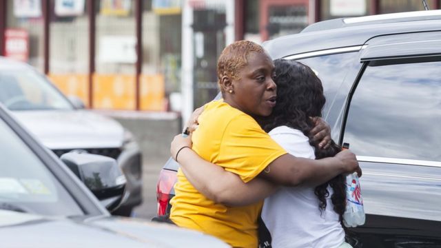 Two people hug each other near the crime scene.