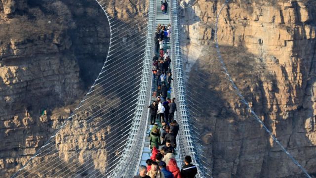 Tourists walk on the glass-bottomed suspension bridge at Hongyagu Scenic Area on December 26, 2017 in Pingshan, Hebei Province of China.