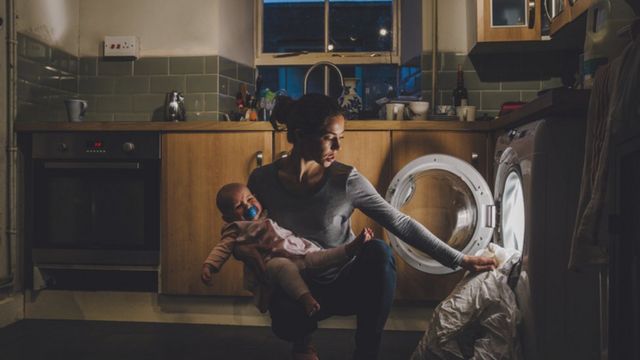 Mãe cuidando de bebê e lavando roupa