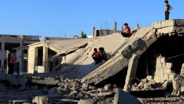 Niños se deslizan sobre un techo derrumbado en la ciudad de Daraa.