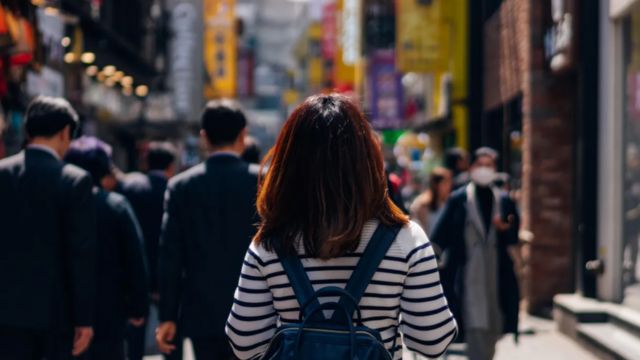 Una mujer camina por una calle transitada en Corea del Sur.