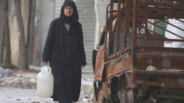 امرأة مسنة تحمل قارورة للمياه في منطقة حلب القديمة التي تسيطر عليها المعارضة