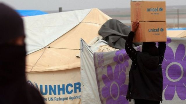 A woman carries boxes of humanitarian aid supplied by Unicef at a refugee camp in Syria's north-eastern Hassakeh province on February 26, 2018