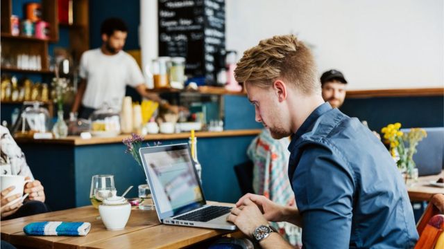 Un hombre frente a una laptop en un café