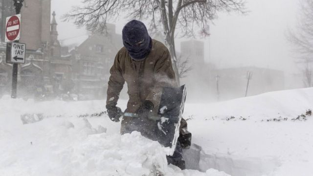 a man in a city "Buffalo" in New York State, he struggles to clear his driveway of heavy snow