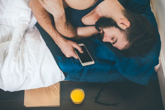 Homem dorme com o celular na mão