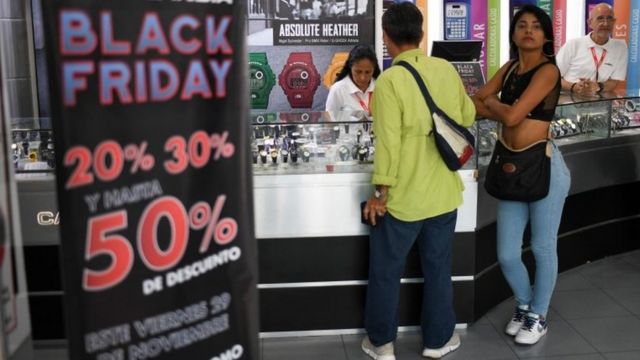 Un hombre y una mujer en una tienda de relojes con ofertas por el Black Friday