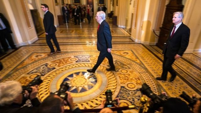 Senate Majority Leader Mitch McConnell (C) walks to the Senate floor at the start of the trial