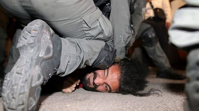 تصویر یکی از فعالان برجسته فلسطینی در تظاهرات روز ۴ ماه مه در حالی که افسر پلیس اسرائیل روی صورتش زانو زده است