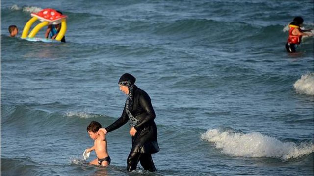 امرأة في البحر ترتدي البوركيني مع طفل