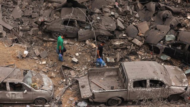 2023年10月9日凌晨，以色列连夜空袭加沙城沙蒂难民营后，一名男子在遭受严重轰炸的社区废墟中行走
