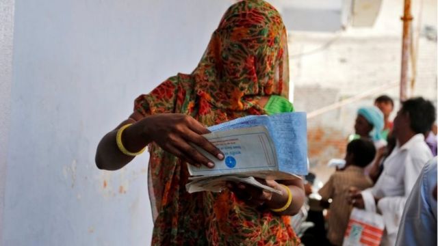 अहमदाबाद के एक गांव में अपने बैंक दस्तावेजों की जांच करती एक महिला