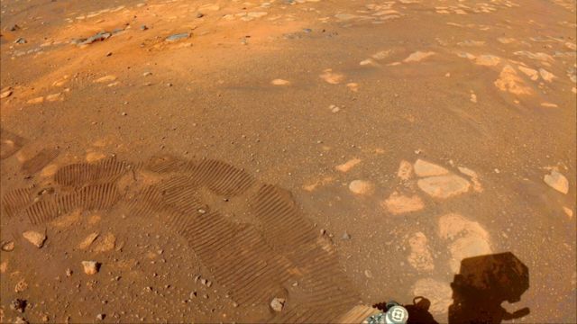 Rocas y polvo en la superficie de Marte, también pueden verse las huellas de Perseverance