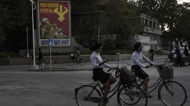 (캡션) 개성 시내에서 손전화(휴대폰)를 보고 있는 자전거를 탄 여학생