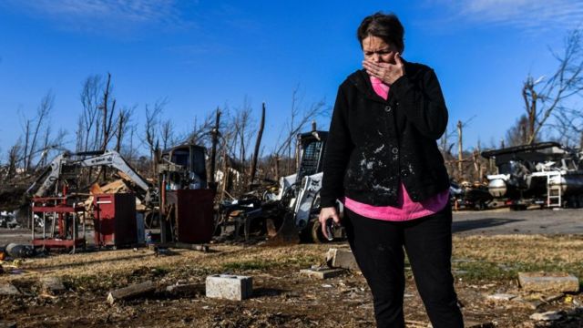 A woman cries in front of a pile of debris after tornadoes that affected five states in the United States.