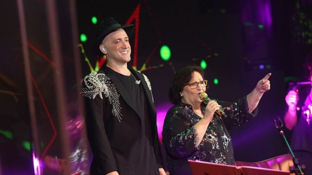 Paulo Gustavo sorri ao lado da mãe no palco, que canta