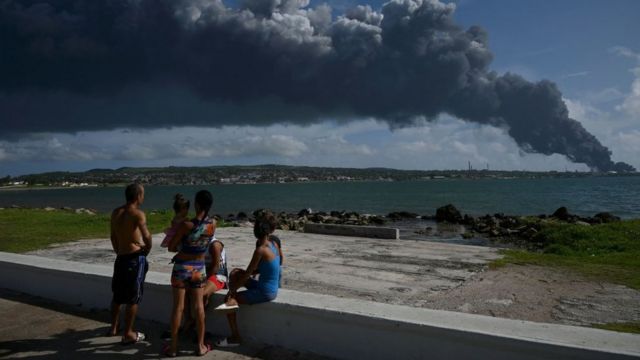 People observe the enormous fumarole of the fire in Matanzas.