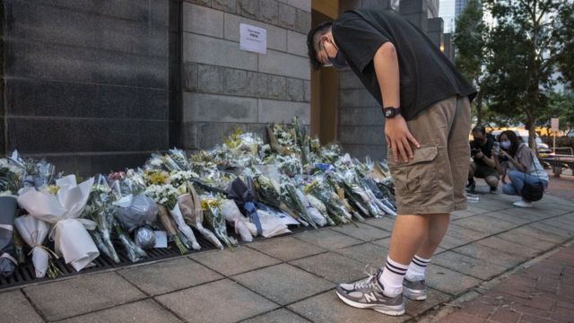英國駐香港總領事館外一位男士向市民留下悼念英女王伊麗莎白二世的花堆鞠躬（9/9/2022）