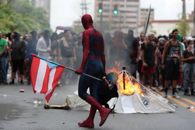 Homem vestido de super-herói carrega bandeira de Porto Rico em protesto na capital, San Juan