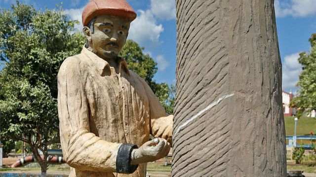 Escultura de un hombre sacando la sabia de un árbol