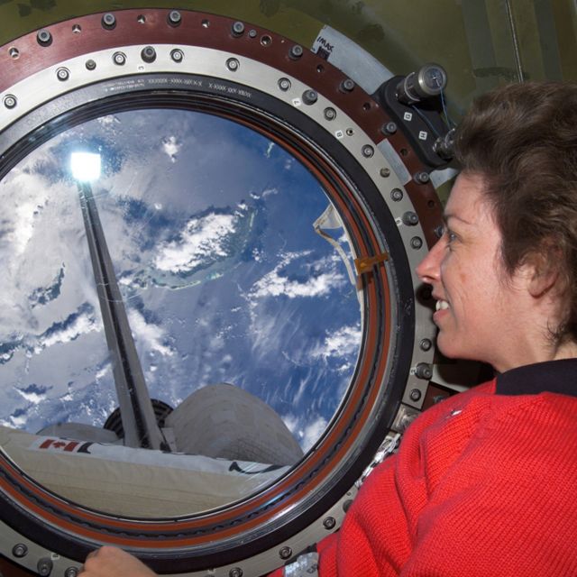 Ellen Ochoa mira a la Tierra desde una ventana de la Estación Espacial Internacional.