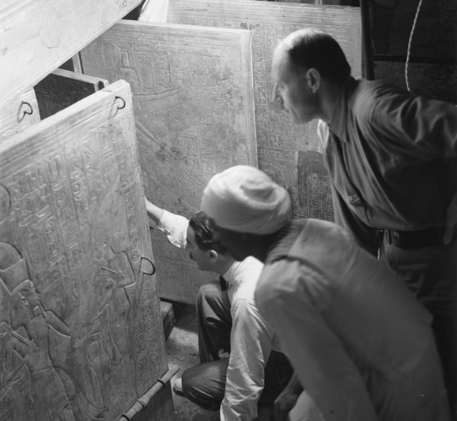 Howard Carter, su asistente Arthur Callender y un egipcio no identificado abren las puertas de un santuario dorado dentro de la tumba de Tutankamón.
