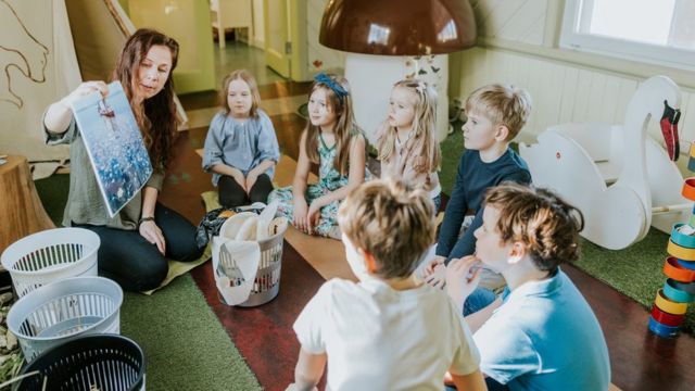 Maestra rodeada de niños en un salón de clases en Estonia.