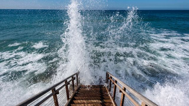 Mar revolto batendo contra uma escada de madeira
