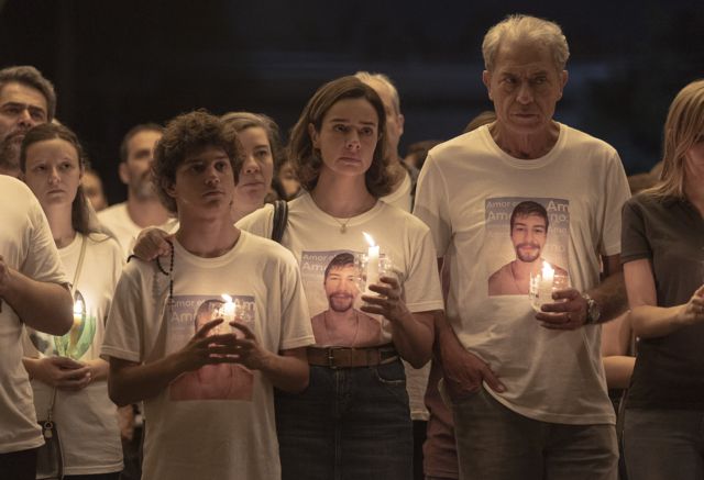 Atores Pedro Sol, Raquel Karro e Paulo Gorgulho segurando velas em vigília durante cena da minissérie 'Todo Dia A Mesma Noite', da Netflix