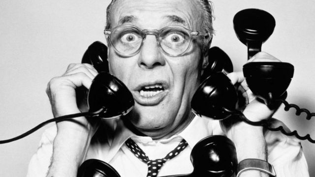 Un hombre atendiendo muchos teléfonos, en una fotografía en blanco y negro