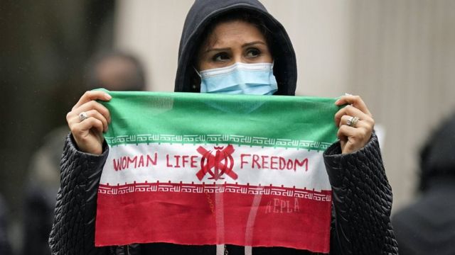 Una mujer sostiene cartel de protesta con el lema "Mujer, vida y libertad".