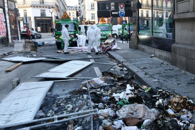 Employees clean up burnt garbage and damage in a street the day after clashes during protests over French government's pension reform in Paris, France, March 24, 2023.