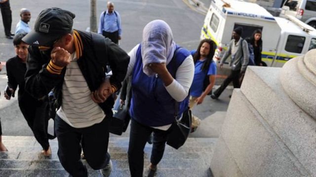 Lavona Solomon (le visage couvert) arrive à la Haute Cour du Cap pendant son procès.