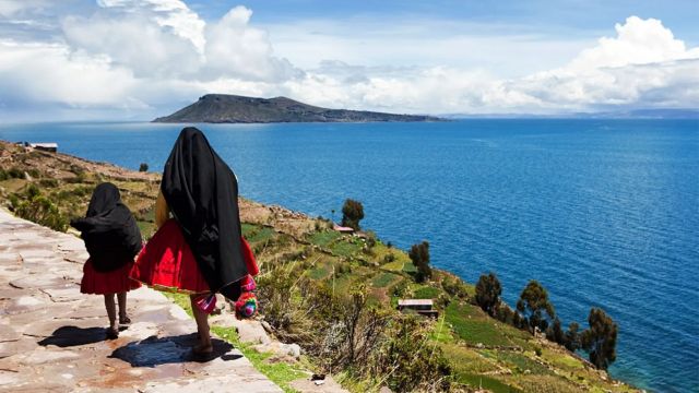Una mujer camina junto a una niña al borde del Lago Titicaca