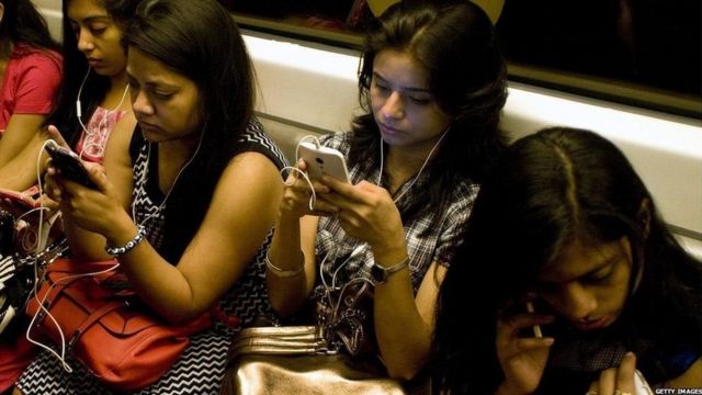 મેટ્રો ટ્રેનમાં મોબાઇલ ફોન વાપરતી છોકરીઓ