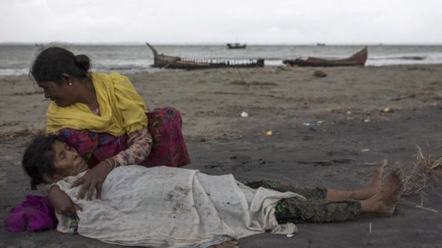 An elderly Rohingya woman is comforted after the wooden boat they were travelling on from Myanmar crashed into the Bangladeshi shore and tipped everyone out (12 September 2017)